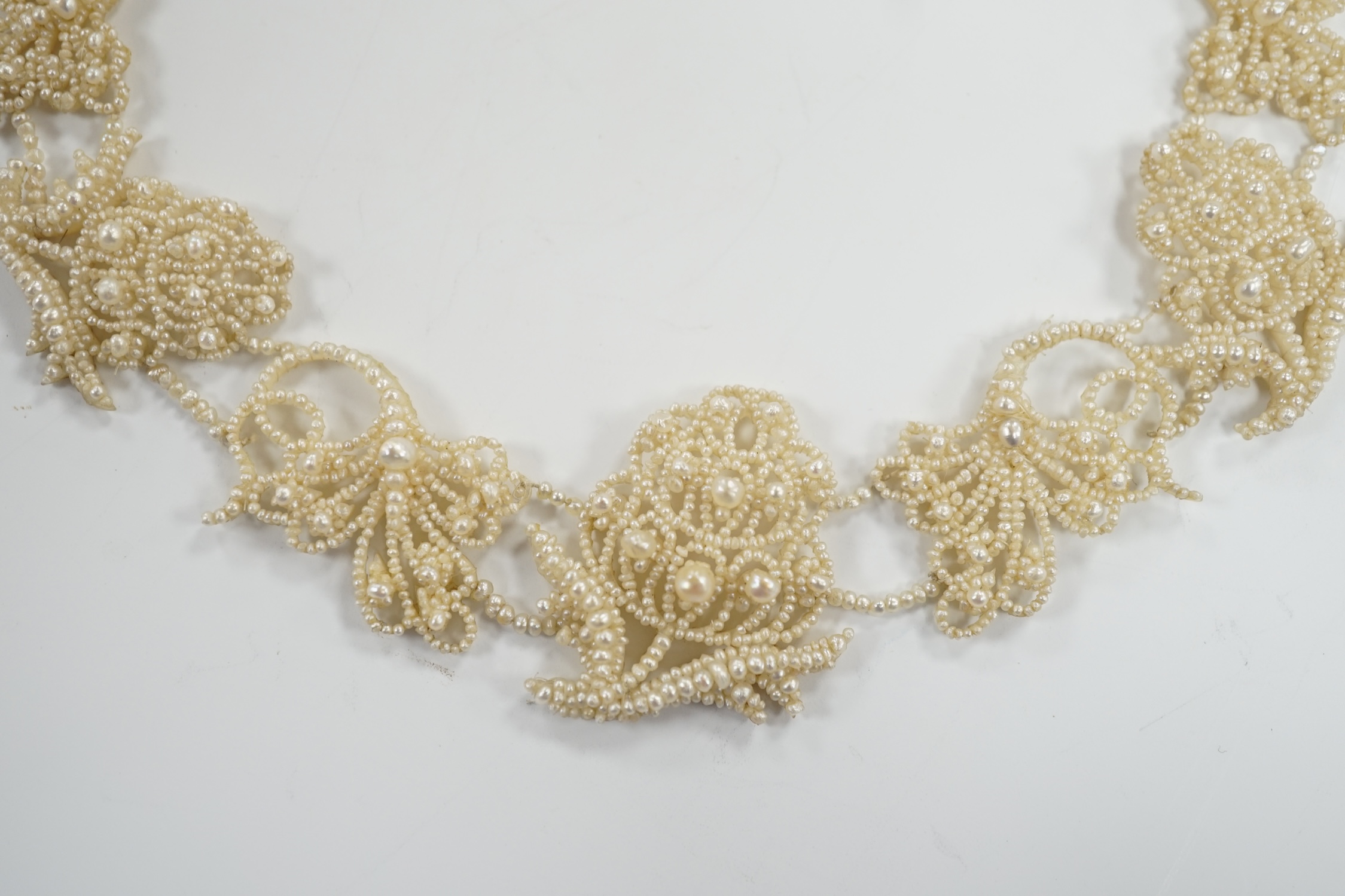 A cased Regency twin strand seed pearl choker necklace with scrolling floral motifs and yellow metal clasp, 34cm.